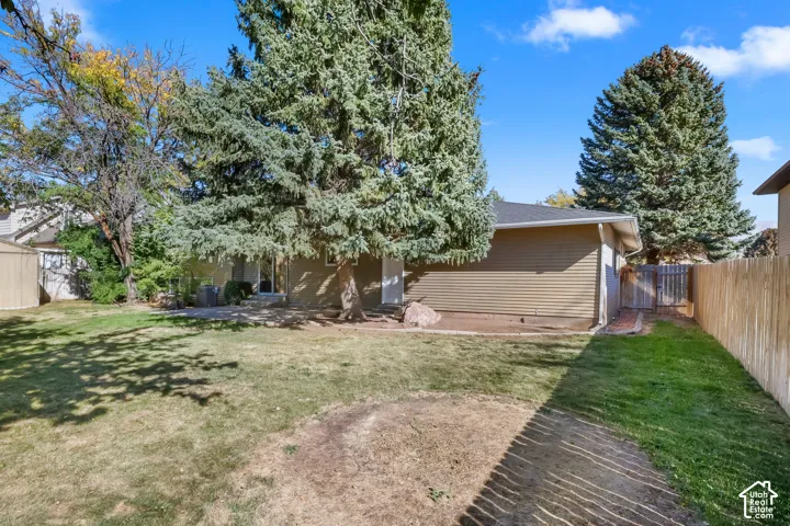 Expansive backyard with a wood privacy fence, mature trees, and a storage shed