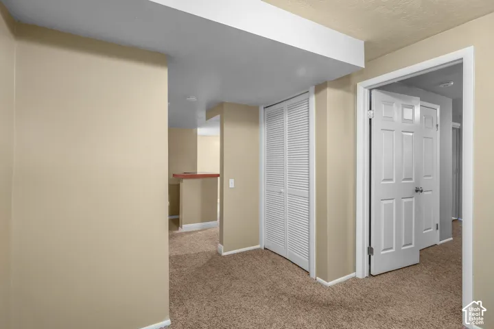 Neutral tone wall paint, textured carpeting, white bi-fold closet doors, white panel doors, and a wood-finish bar counter