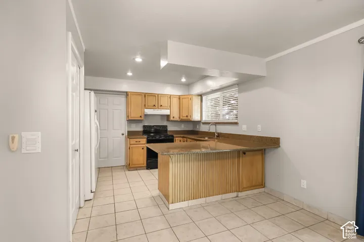 Kitchen featuring wood cabinetry, a tiled floor, recessed lighting, a window with blinds, and an integrated breakfast bar