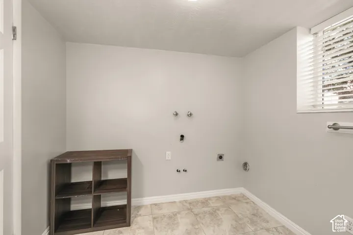 Utility space with tiled flooring, a window featuring horizontal blinds, and a wall-mounted towel bar