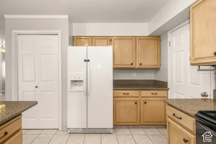 Kitchen featuring light wood cabinetry, white appliances, and speckled countertops