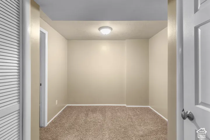 Carpeted room with neutral wall paint, overhead flush-mount lighting, and white trim