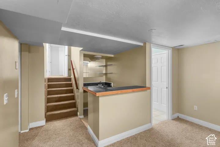 Built-in wet bar with a single basin sink, open shelving, and a dark countertop