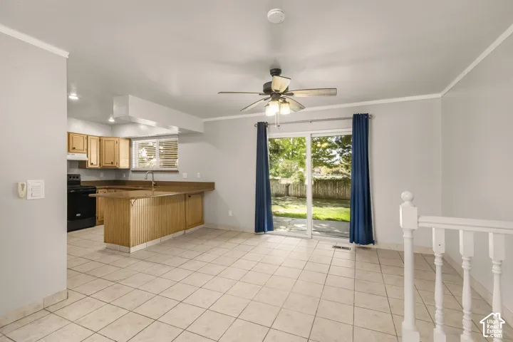 Tile flooring, light wood cabinetry, built-in kitchen island, stainless-steel sink, and sliding glass door to exterior