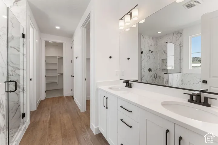 Dual vanity with white cabinetry, matte black hardware, and an expansive wall-mounted mirror
