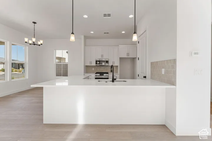 Open-concept kitchen with a large island, white cabinetry, stainless steel appliances, and tile backsplash