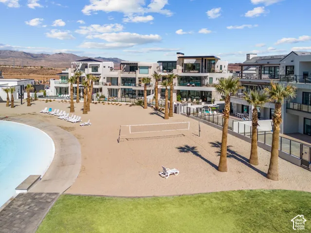 Expansive outdoor sand area with a volleyball net, bordered by mature palm trees
