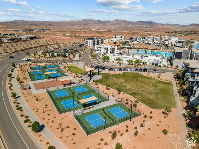 Multiple pickleball courts with perimeter fencing, a large central grassy area, and paved walking paths