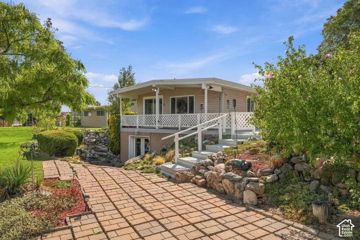 Exterior residence featuring siding, a wraparound deck with lattice railing, and a paver walkway