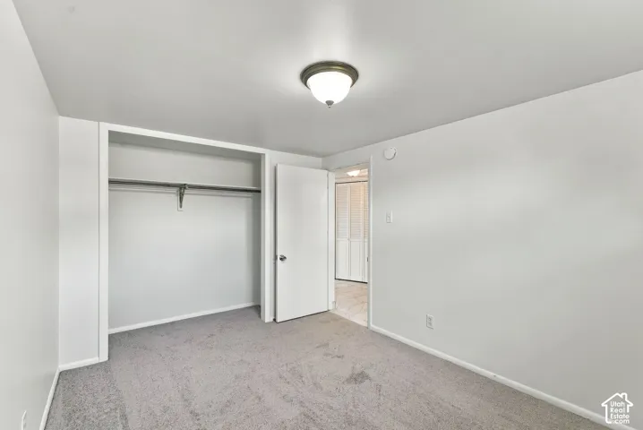 Plush carpeting, recessed closet with hanging rod, flush mount lighting fixture, neutral wall color, and white trim