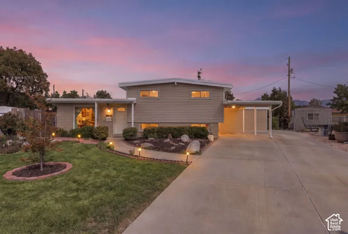Split-level exterior with horizontal siding, a covered carport, and a concrete driveway