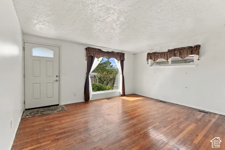 Hardwood flooring, front entry door with transom light, and a large window