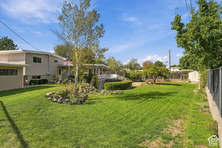 Expansive grassy yard with mature trees, a rock garden, and manicured shrubbery