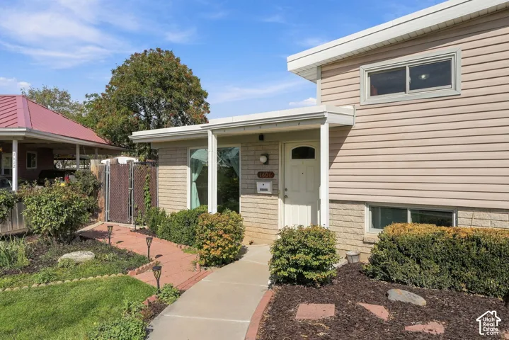 Split-level residence featuring a brick and siding exterior, a covered entryway, and a concrete walkway