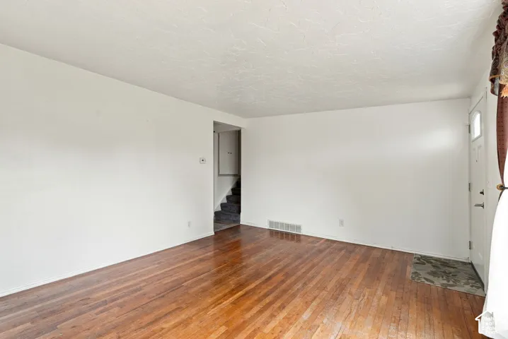 Wood-finish flooring throughout, white wall finishes, and a white entry door with a frosted glass insert