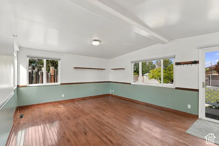 Hardwood flooring, painted walls with wainscoting, exposed ceiling beams, and a ceiling-mounted light fixture