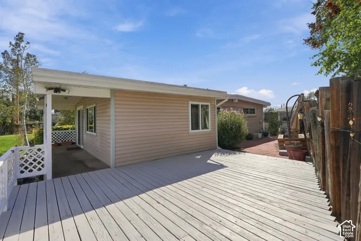 Expansive exterior deck with an attached covered patio, featuring vinyl siding and a brick-paved area