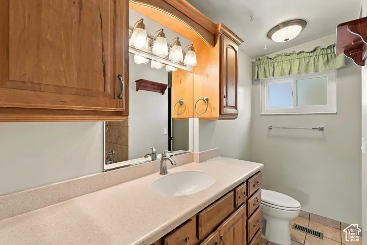 Vanity with integrated sink, wood-finish cabinetry, and overhead lighting