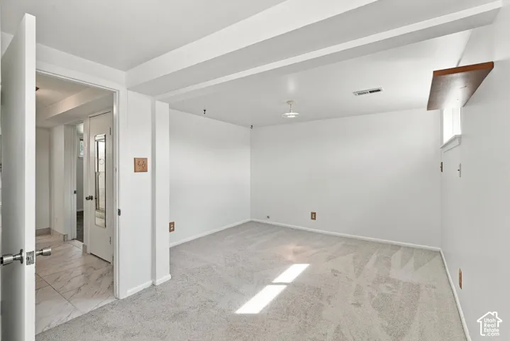 Recessed lighting, wood-finish floating shelf, light gray carpet, white painted walls, and a window with natural light