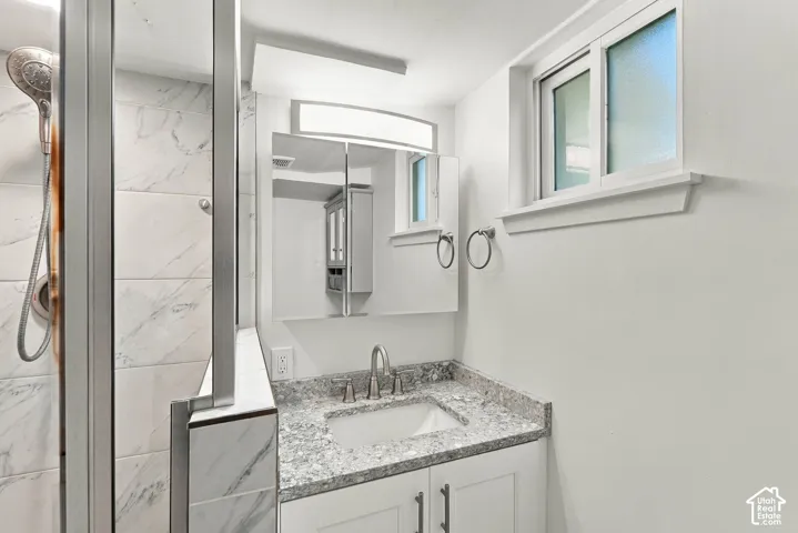 White shaker-style vanity with a granite countertop and integrated sink