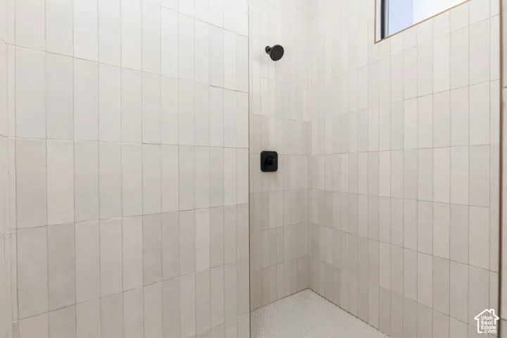 Shower with vertical subway tile, matte black fixtures, and a glass enclosure