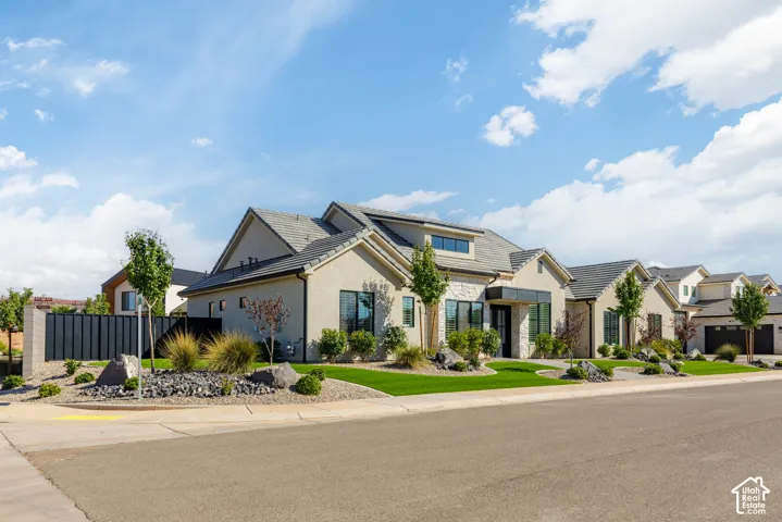 Modern stucco exterior with stone accents, a dark-tiled roof, and integrated garage