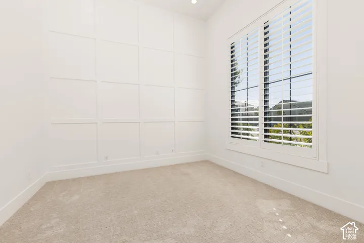 White wall paneling, plantation shutters, large window, recessed lighting, and carpet flooring