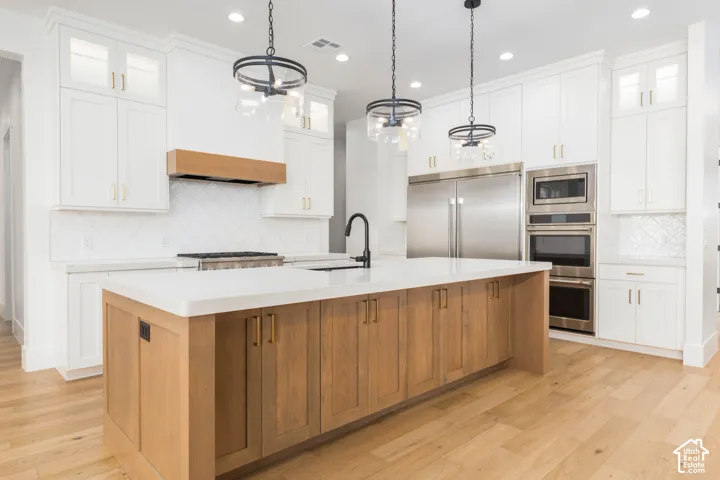 Central island with wood-finish cabinetry and a light-toned countertop, complemented by three hanging light fixtures