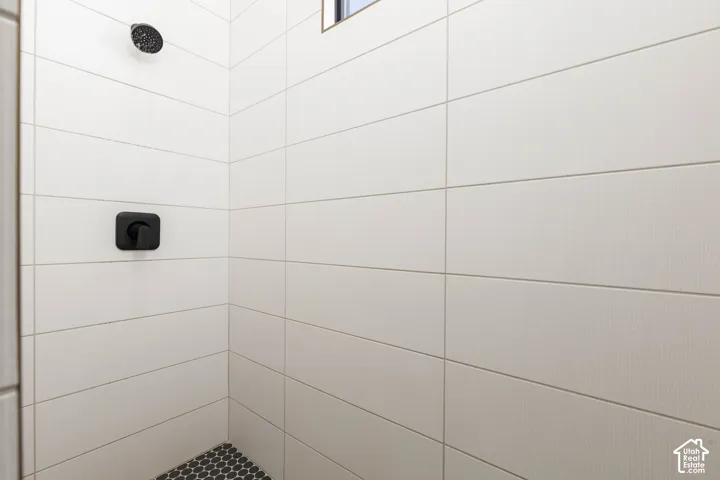 White rectangular wall tiling, matte black shower head, matte black shower control, and dark hexagonal floor tiling