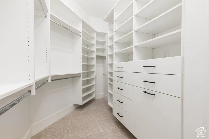 Integrated custom closet system with extensive shelving, multiple hanging rods, built-in drawers with matte black hardware, and neutral-toned carpeting