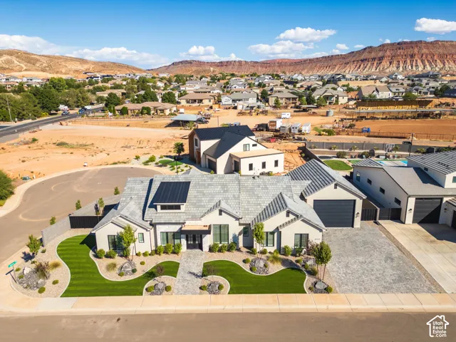 Contemporary residence with a gray tile roof, integrated solar panels, and a paver driveway