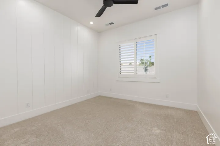 Carpeted flooring, recessed lighting, white shiplap wall treatment, window with plantation shutters, black ceiling fan
