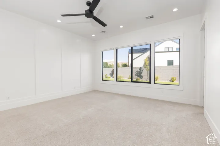 Recessed lighting, large picture windows, ceiling fan, white paneled accent wall, and light-toned carpeting