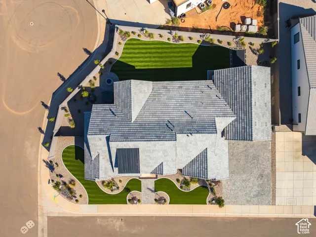 Expansive lot featuring a manicured lawn, paved driveway, and varied landscaping elements
