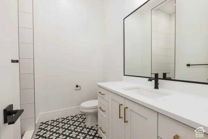 White shaker cabinetry with brass hardware, a black-framed vanity mirror, and an integrated white sink with a matte black faucet