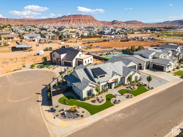 Contemporary architectural style with a light exterior finish, gray tile roofing, and a professionally landscaped front yard featuring artificial turf and decorative rock elements