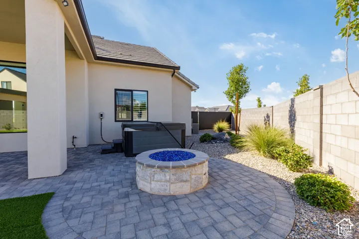 Paver patio with a stone fire pit, built-in spa, and low-maintenance landscaping