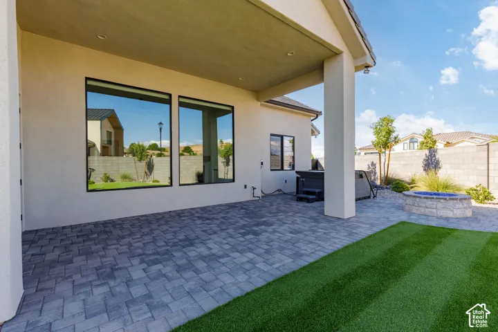 Expansive covered patio with large black-framed glass doors and windows overlooking a manicured lawn and professionally installed herringbone-pattern pavers