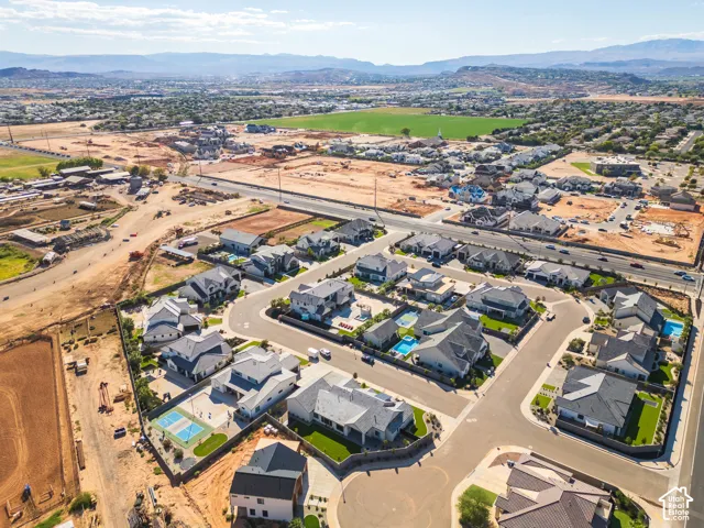 Aerial perspective showcasing residential properties with gray roofs and manicured lawns, some featuring private swimming pools