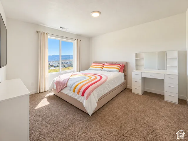 Neutral-toned carpeting, ample natural light from a large window, recessed lighting, and white walls