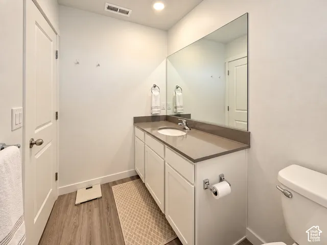 White vanity with a single basin sink, integrated countertop, and large wall-mounted mirror