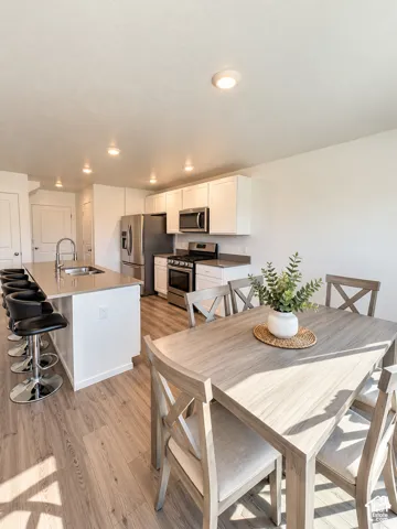 Kitchen with stainless steel appliances, white cabinetry, recessed lighting, and wood-finish flooring