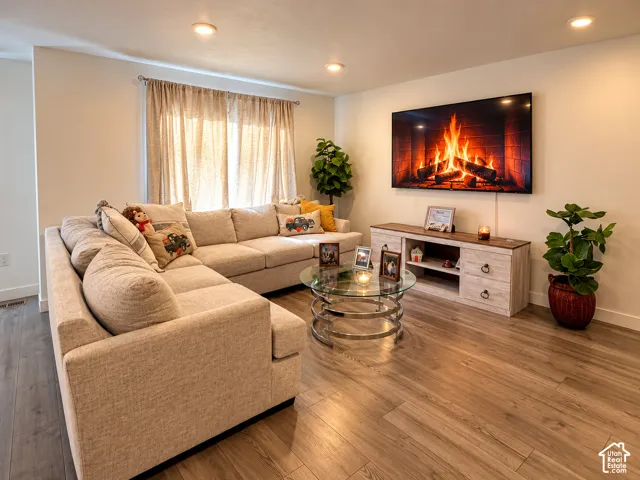 Recessed lighting illuminates the living area featuring wood-finish flooring