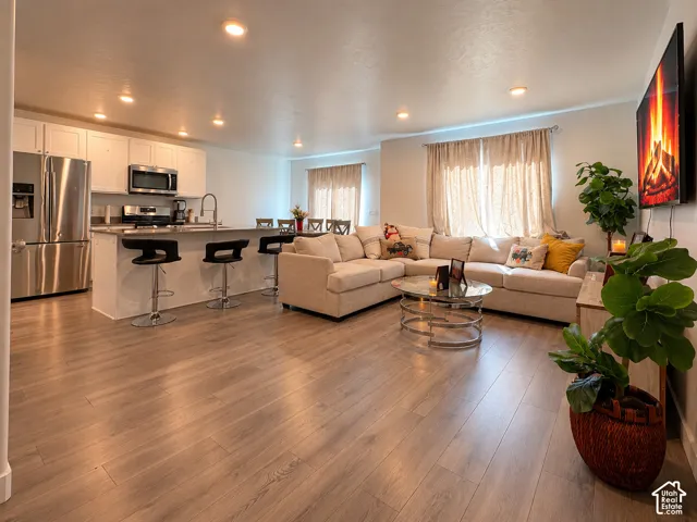 Open concept living space featuring wood-finish flooring, recessed lighting, and a kitchen island with seating