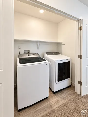 Dedicated laundry closet featuring a built-in shelf, recessed lighting, and wood-finish flooring