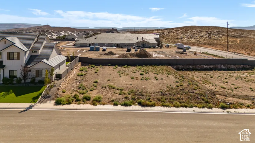 Expansive undeveloped lot with street frontage, flat terrain, and a concrete retaining wall