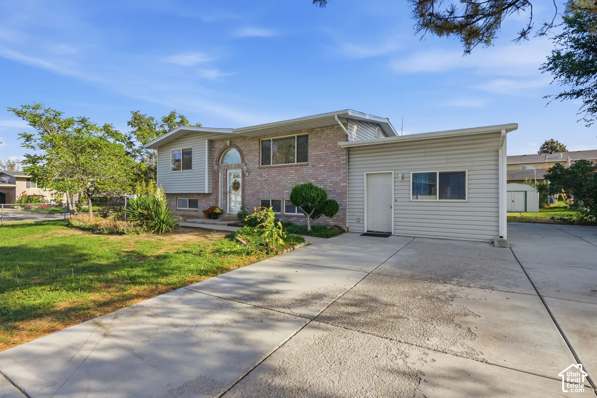 Split-level residence featuring brick and siding exterior, arched entry, and an attached garage
