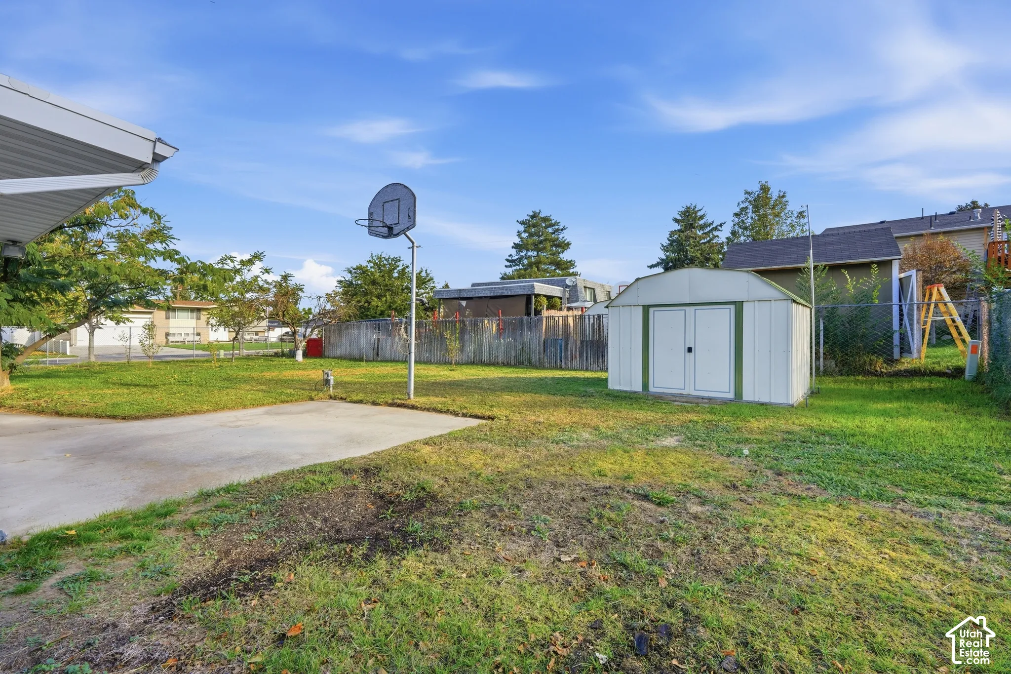 Expansive backyard featuring a concrete patio, a detached storage shed, and perimeter fencing
