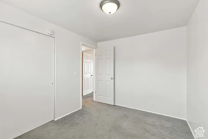 Neutral wall finishes, recessed ceiling light fixture, white interior door, and gray carpet