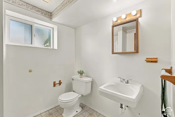 Wall-mounted vanity sink, framed mirror with integrated lighting, and white toilet